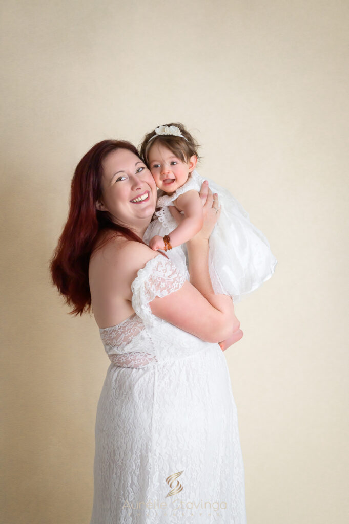Maman en robe blanche portant son enfant, photographe baptême Voiron